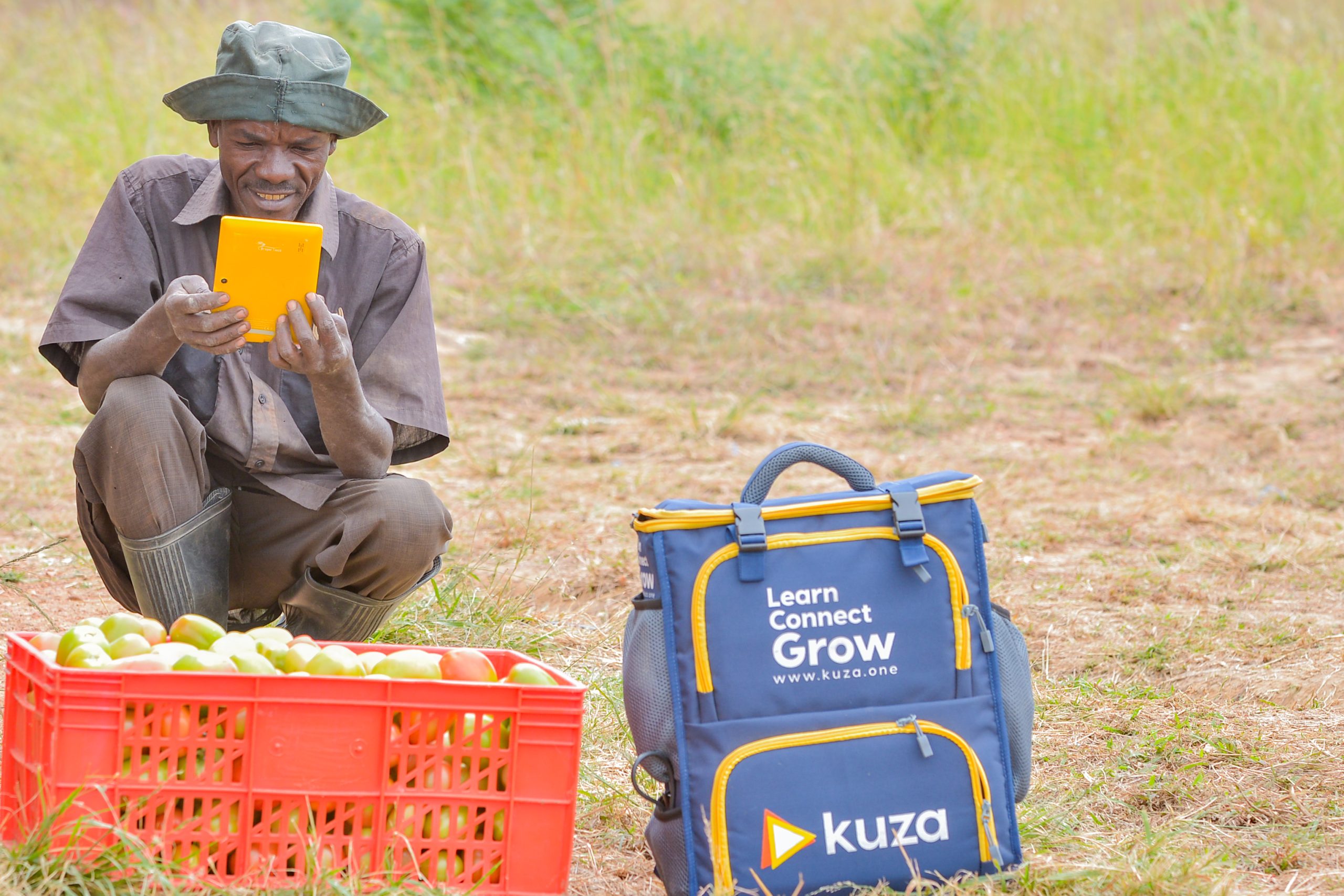 A smallholder farmer using a Kuza digital learning tablet beside a Kuza kit