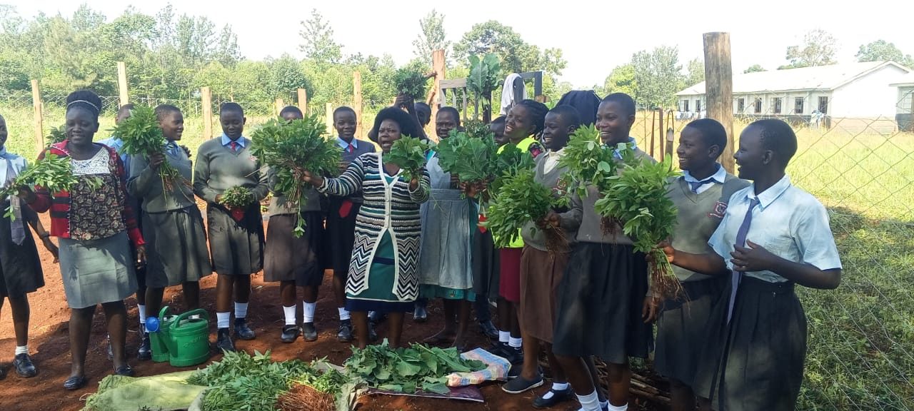 Young learners holding vegetables harvested from their school demonstration plot